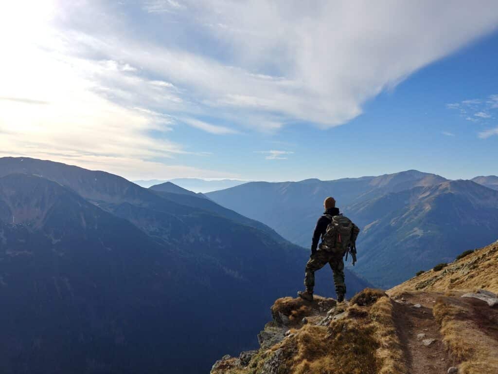 A Man Standing On Top Of A Mountain Overseeing A Canyon