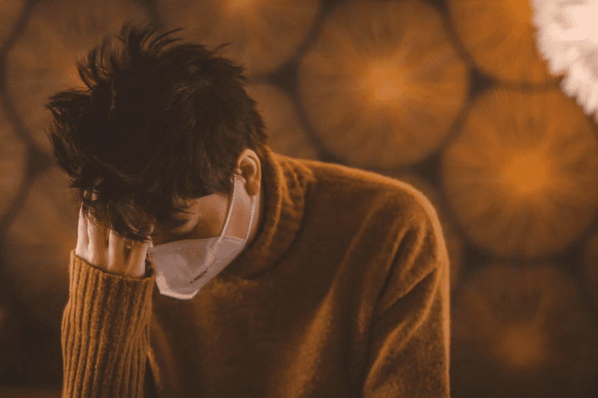 a man with his mask on trying to cope with losing a loved one during pandemic