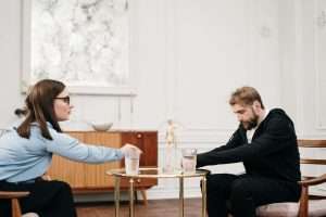 A life coach demonstrating assertive communication techniques to a client during a session
