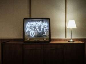 vintage black CRT TV turned-on near lighted table lamp