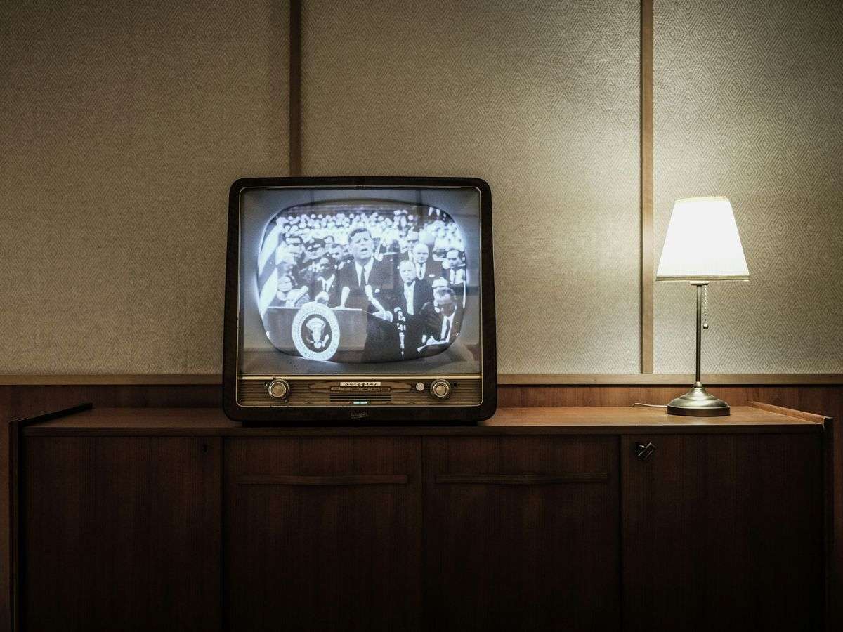 vintage black CRT TV turned-on near lighted table lamp